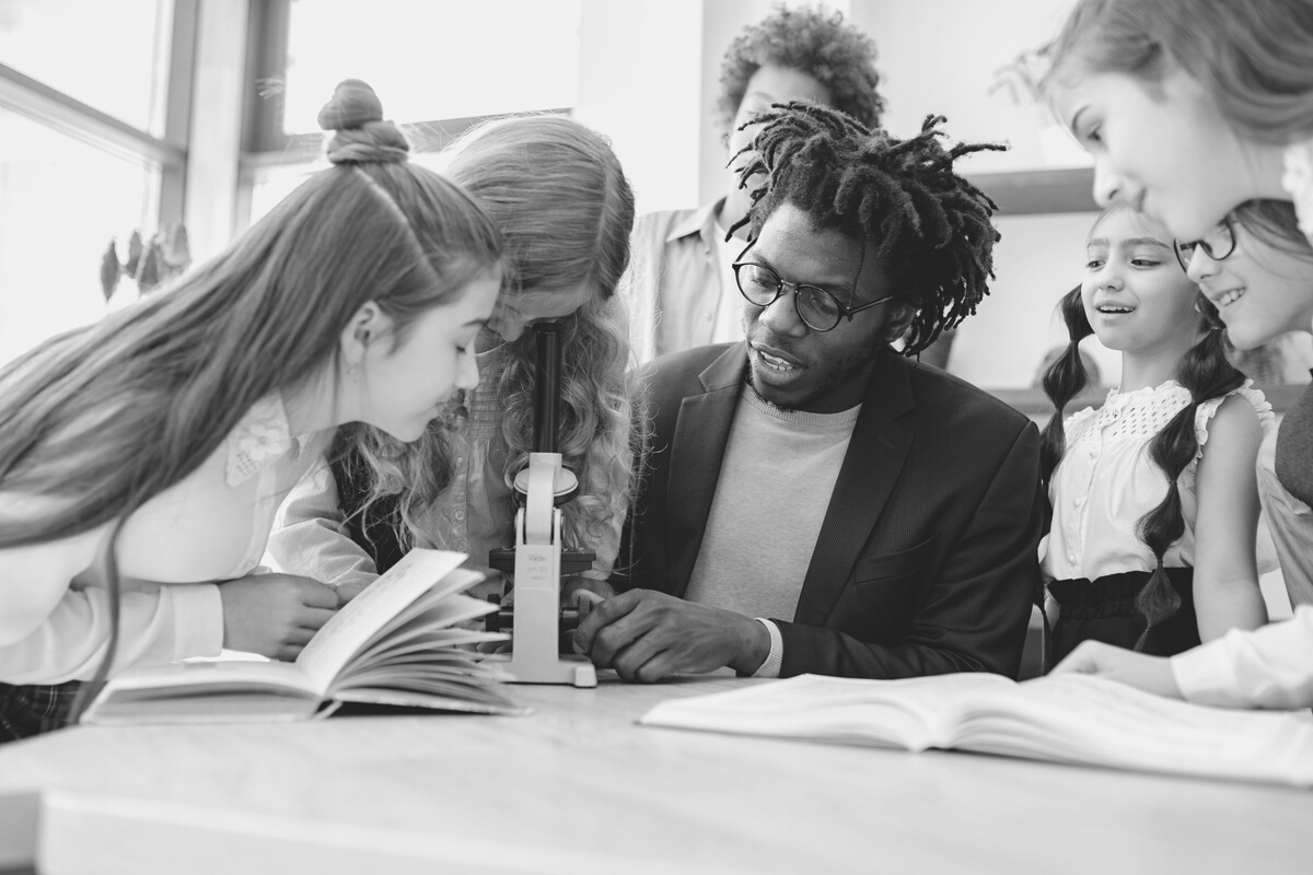 A Man Teaching Students How to Use a Microscope